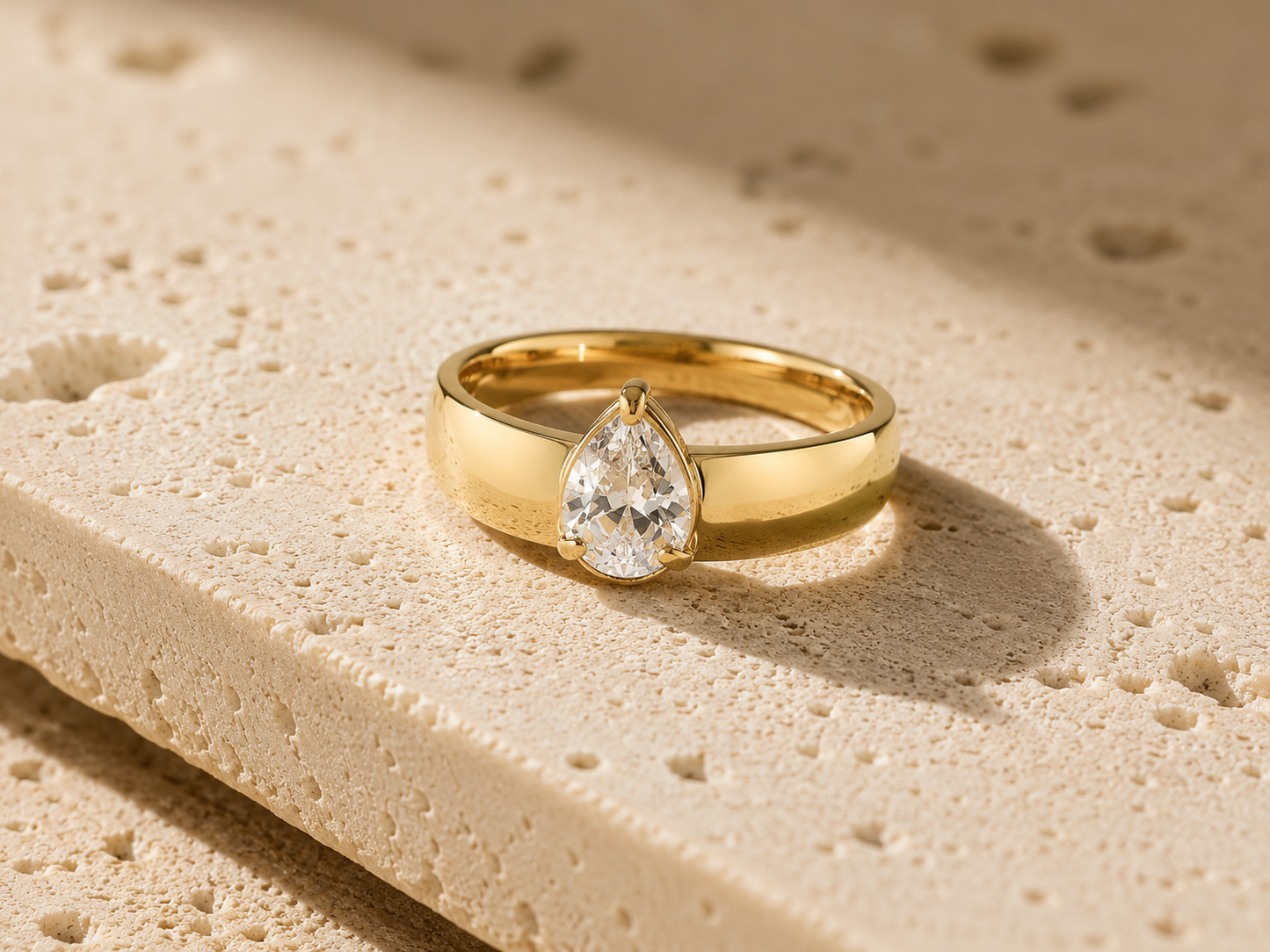 Rosemere Alessia pear-cut solitaire gold ring on natural stone in soft daylight