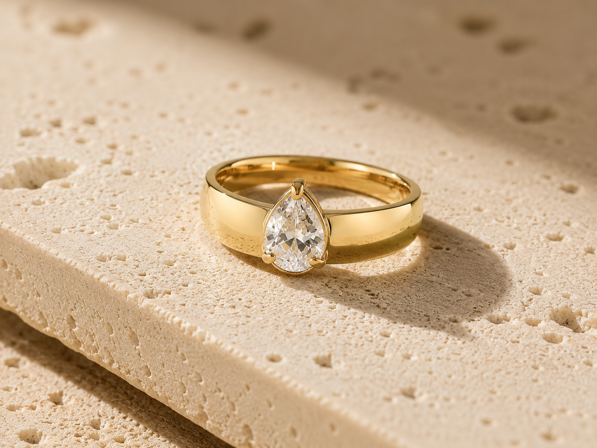 Rosemere Alessia pear-cut solitaire gold ring on natural stone in soft daylight