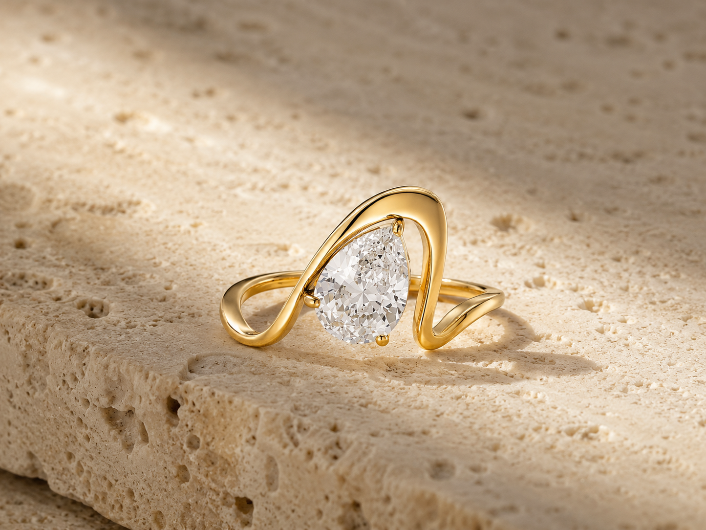 Rosemere Celeste pear-cut gold ring on natural stone in soft daylight