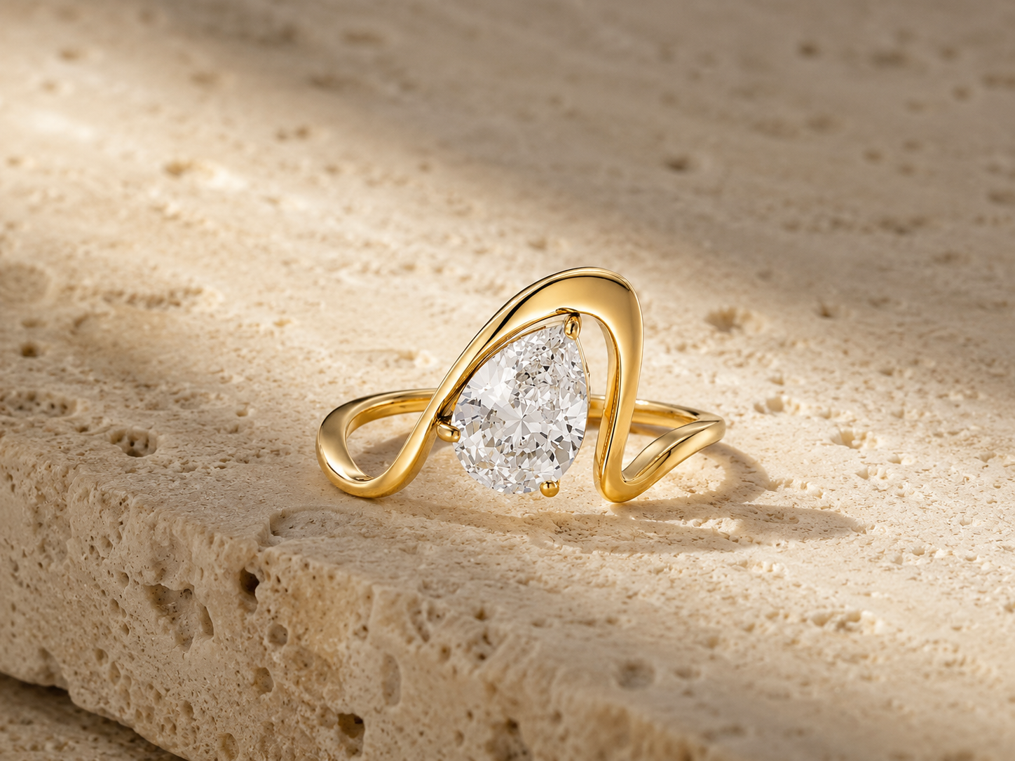 Rosemere Celeste pear-cut gold ring on natural stone in soft daylight