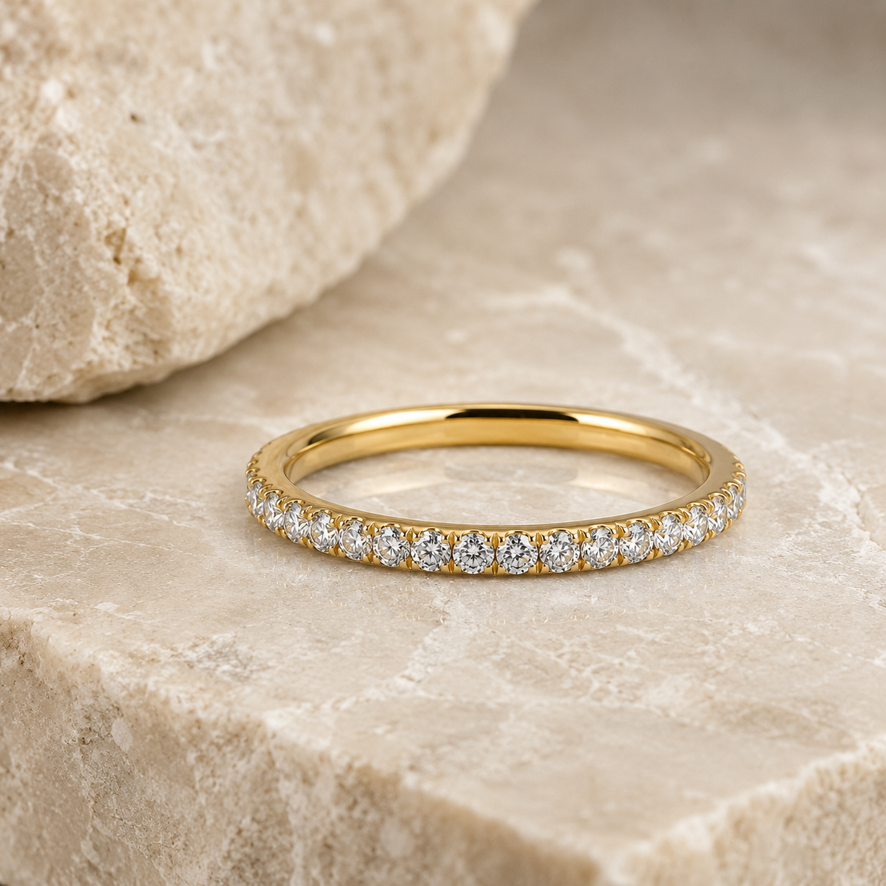 Rosemere Eterna gold pavé eternity ring on natural stone in soft daylight